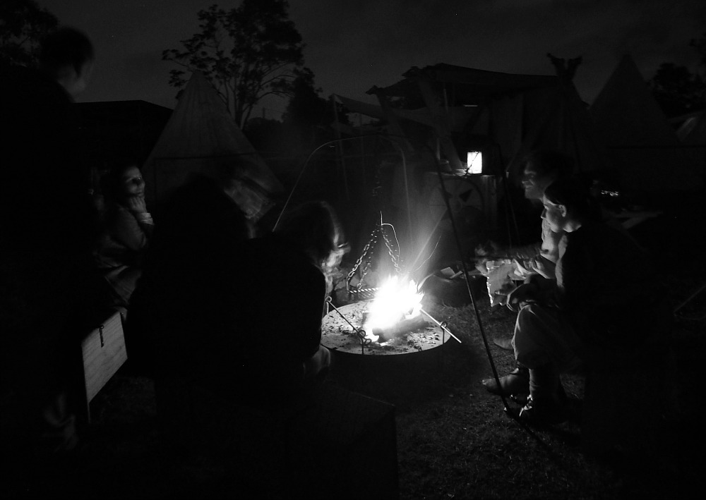 people around campfire black and white